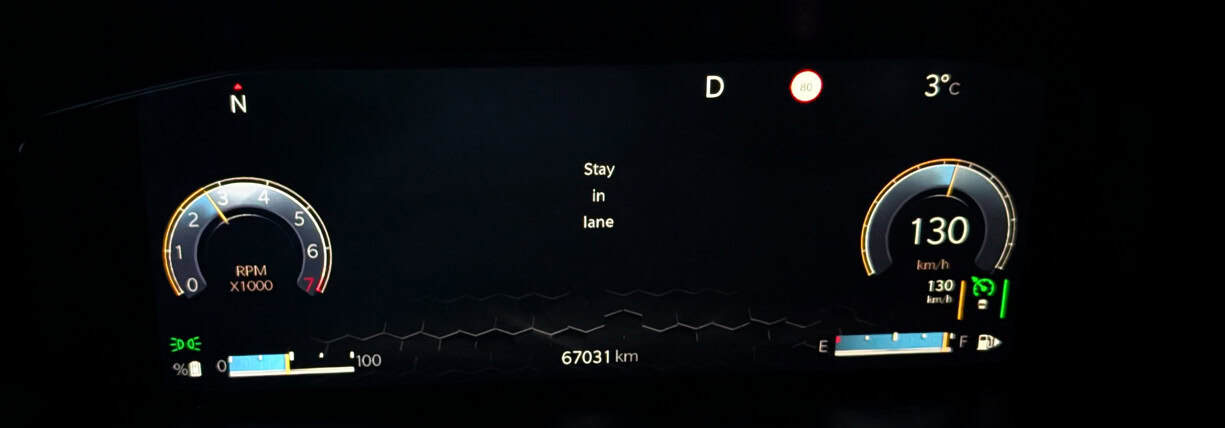 Close-up of a car dashboard showing speed, RPM, and navigation alerts.
