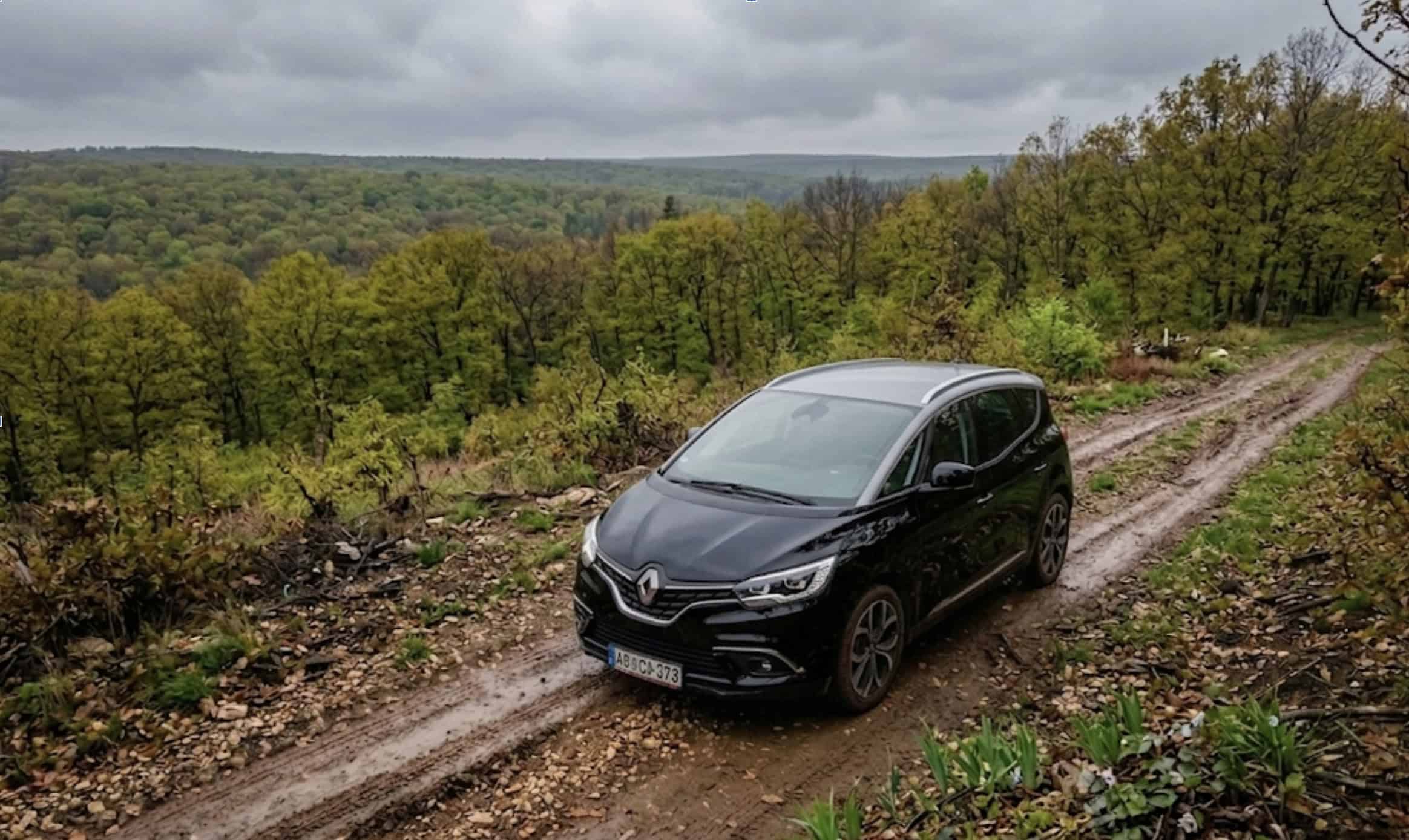 Black Renault Grand Scenic driving on muddy off-road track in countryside.